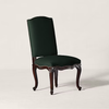 A classic high-back dining chair with dark forest green velvet upholstery and a carved dark brown wooden frame with nailhead trim, shown on a light beige studio background.
