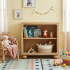 Children's room with wooden bookshelf, toys, and books against a yellow wall.