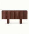 A modern wooden sideboard or console table with a dark brown finish, featuring vertical fluted paneling on the front and two blocky legs, shown against a plain white background.