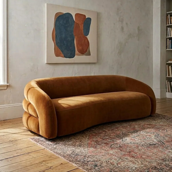 Brown sofa in a room with abstract art on the wall and books on a shelf.