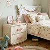 Children's bedroom with a bed and nightstand, featuring toys and decorative items.