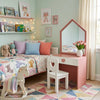 Children's bedroom with pink vanity, colorful bedding, and toys.