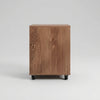 Wooden cabinet on wheels in a room with a light blue wall and wooden floor.