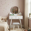 Small white vanity table with round mirror in a bedroom setting.