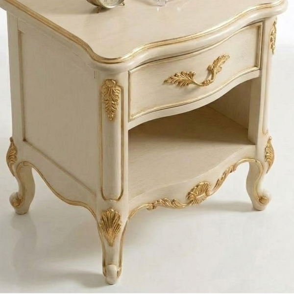 An elegant French-style nightstand in cream with ornate gold leaf detailing, featuring a single drawer with a curved gold handle and a lower shelf.