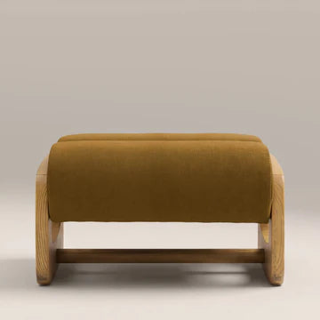 Wooden ottoman with a mustard yellow cushion on a neutral background