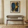 Modern bench against a wall with abstract art above it in a room setting.