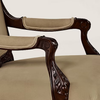Close-up of a classic wooden armchair with carved dark brown cabriole legs and beige upholstered seat and back cushions.
