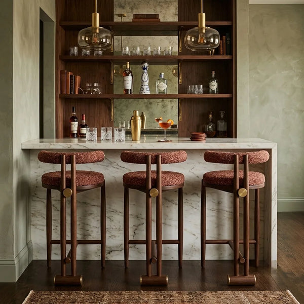 Bar area with wooden shelves, bar stools, and a marble countertop.