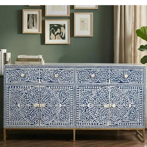 Decorative cabinet with intricate patterns in a room with green walls and framed art.