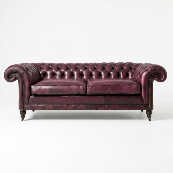 A classic Chesterfield loveseat sofa upholstered in deep burgundy leather, featuring button tufting, rolled arms, and dark wooden legs, photographed against a plain white studio background.