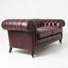 A classic Chesterfield loveseat sofa upholstered in distressed burgundy leather, featuring tufted back cushions, rolled arms, nailhead trim, and dark wooden turned legs on a white studio background.