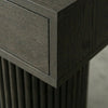 Close-up of a dark gray wood furniture piece showing the grain texture of a drawer front and fluted column base.