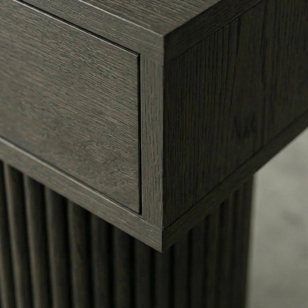 Close-up of a dark gray wood furniture piece showing the grain texture of a drawer front and fluted column base.