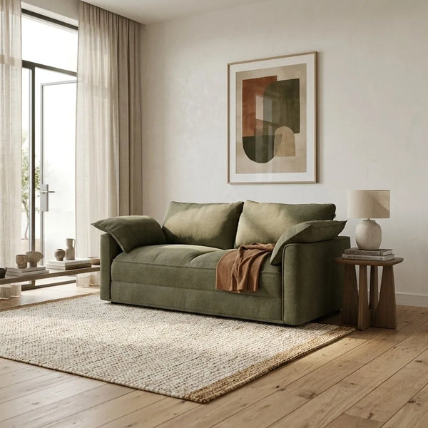 Green sofa in a modern living room with a lamp and artwork on the wall.