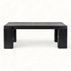 A low rectangular black wooden coffee table with blocky legs, photographed against a plain white background.
