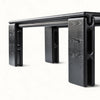 A close-up studio shot of a modern black table with a dark wood grain finish, showing its unique blocky legs and top edge against a clean white background.