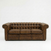 A brown leather Chesterfield loveseat sofa with deep button tufting on the backrest and arms, shown against a plain white studio background.