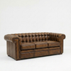 A classic brown leather Chesterfield loveseat sofa with deep button tufting, rolled arms, and brass nailhead trim, photographed against a seamless white studio background.