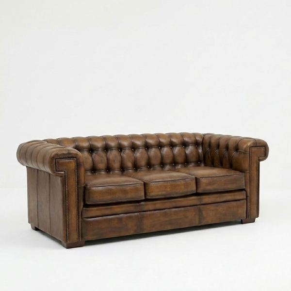 A classic brown leather Chesterfield loveseat sofa with deep button tufting, rolled arms, and brass nailhead trim, photographed against a seamless white studio background.