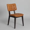 A modern dining chair with a tufted cognac brown leather seat and backrest, supported by a dark brown wooden frame, shown against a neutral gray background.