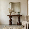 Wooden console table with decorative items against a neutral wall.