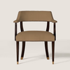 An upholstered armchair with a warm taupe seat and back cushion, dark brown wooden legs, and brass nailhead trim, shown against a light beige background.