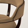 Close-up of a beige upholstered chair with dark brown wooden arms and a decorative line of dark metal nailheads around the curved armrests, set against a plain light background.