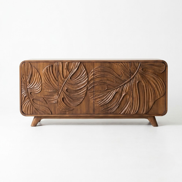 A mid-century modern wooden sideboard featuring three doors with large, hand-carved monstera leaf patterns on the front, supported by two tapered legs, shown against a plain white background.