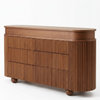 A mid-century modern wooden credenza with a fluted front, rounded top, and small round feet, shown on a clean white background.