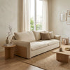 Beige sofa in a living room with a large window, wooden side table, and coffee table.
