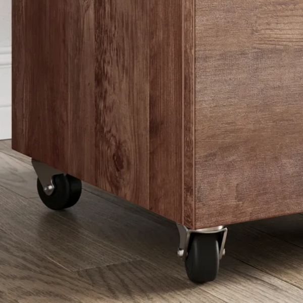 Close-up of a wooden storage unit with wheels on a wooden floor.