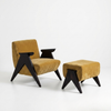 A mid-century modern armchair with a mustard yellow velvet upholstery and black wooden legs, paired with a matching square ottoman, set against a plain white studio background.
