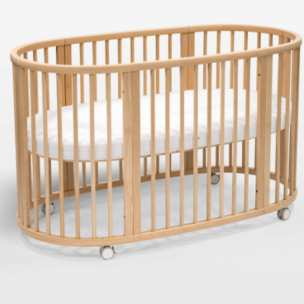 Wooden crib with white mattress on a light background