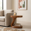 Wooden side table with a candle and books next to a beige sofa in a living room.
