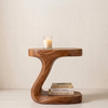Wooden side table with a candle and books on a plain background