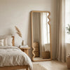 Bedroom with a large floor mirror, bed, and side table.