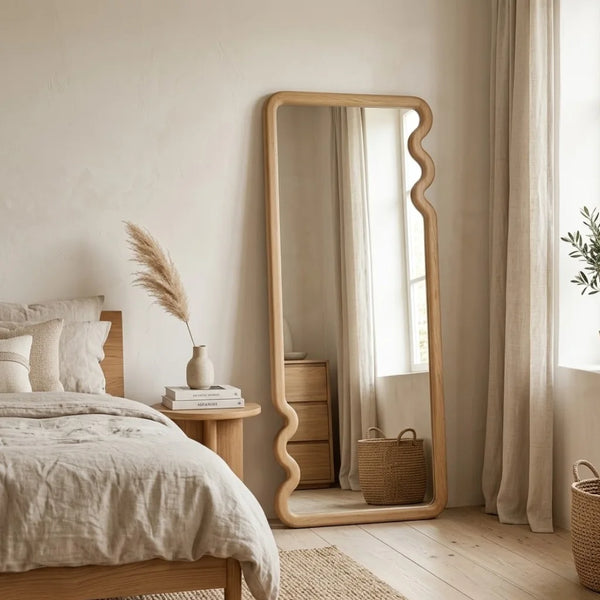 Bedroom with a large floor mirror, bed, and side table.