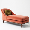 Orange velvet chaise lounge with a green pillow on a white background