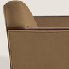 Close-up of a tan upholstered armchair showing the backrest, armrest, and a dark wood arm cap against a light neutral background.