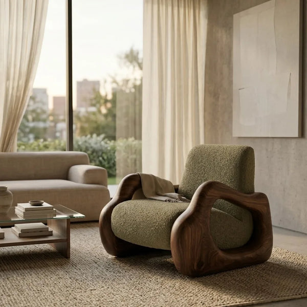 A modern lounge chair with a textured olive green bouclé seat and sculptural dark wood frame, styled in a contemporary living room next to a beige sofa and large windows.