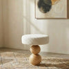 Small round end table with textured boucle fabric top and wooden base .