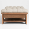 Beige upholstered ottoman with wooden frame on a white background