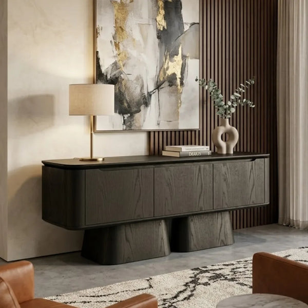 A modern floating media console in a dark wood finish, styled in a contemporary living room setting with a table lamp, books, a ceramic vase, and abstract wall art.