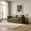Green sofa in a modern living room with a lamp and artwork on the wall.