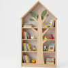 Wooden bookshelf designed like a tree with books and toys on a white background