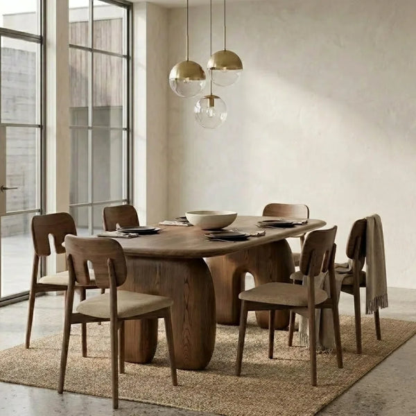 A modern dining room set featuring a dark wood dining table and six matching wooden chairs with light beige upholstered seats, arranged on a woven jute rug under three hanging pendant lights.