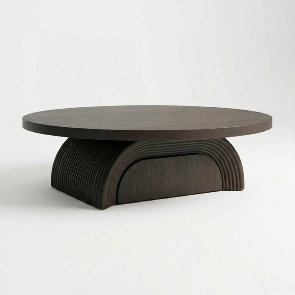 A modern round coffee table with a dark wood top and a sculptural, ribbed semi-circular pedestal base, shown on a clean white studio background.