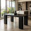 A dark wood dining table with thick blocky legs and a rectangular top, styled in a modern kitchen setting with a concrete floor and large windows.