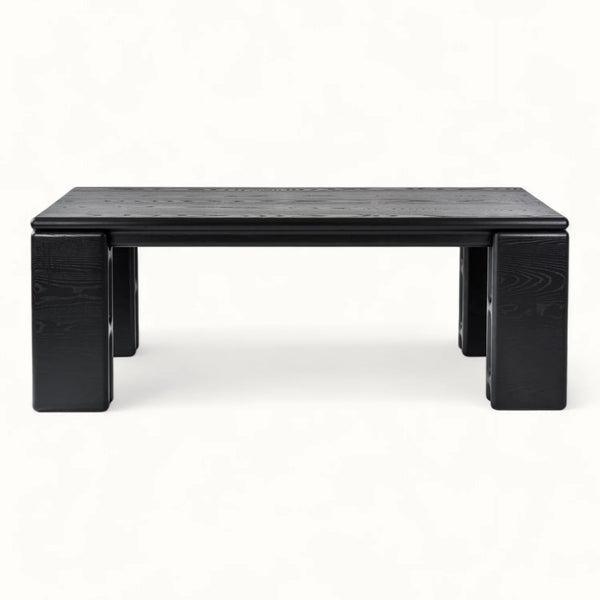 A low rectangular black wooden coffee table with blocky legs, photographed against a plain white background.